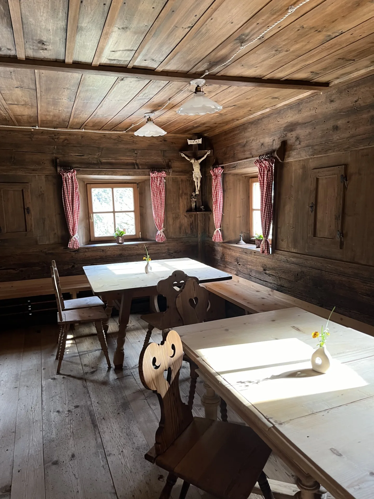Stube tradizionale in legno del maso Orthammer con tavoli, panche e crocifisso d'epoca